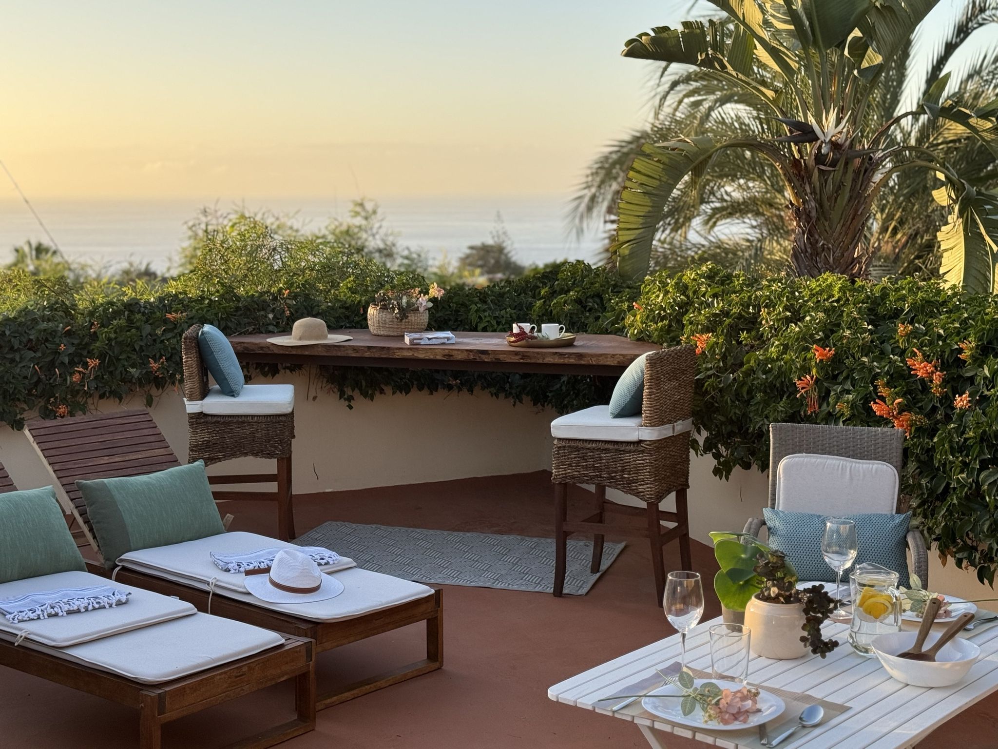 Casita Aquavista: Dachterrasse bei Sonnenuntergang mit Liegen, Bartresen und gedecktem Tisch, im Hintergrund das Meer