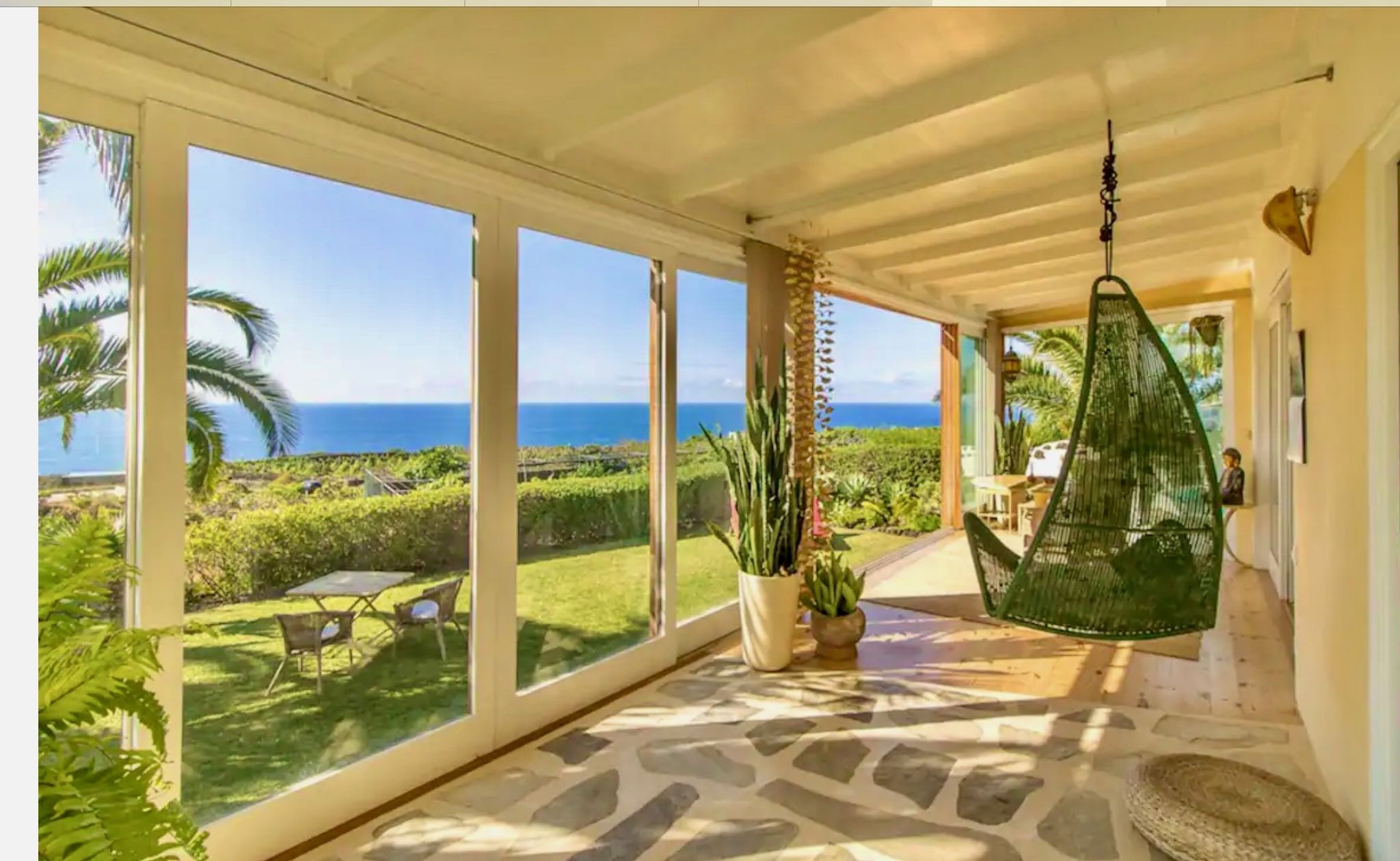 Bellamare: Wintergarten mit Hängesessel und Natursteinboden, Blick über den Garten auf den Atlantik