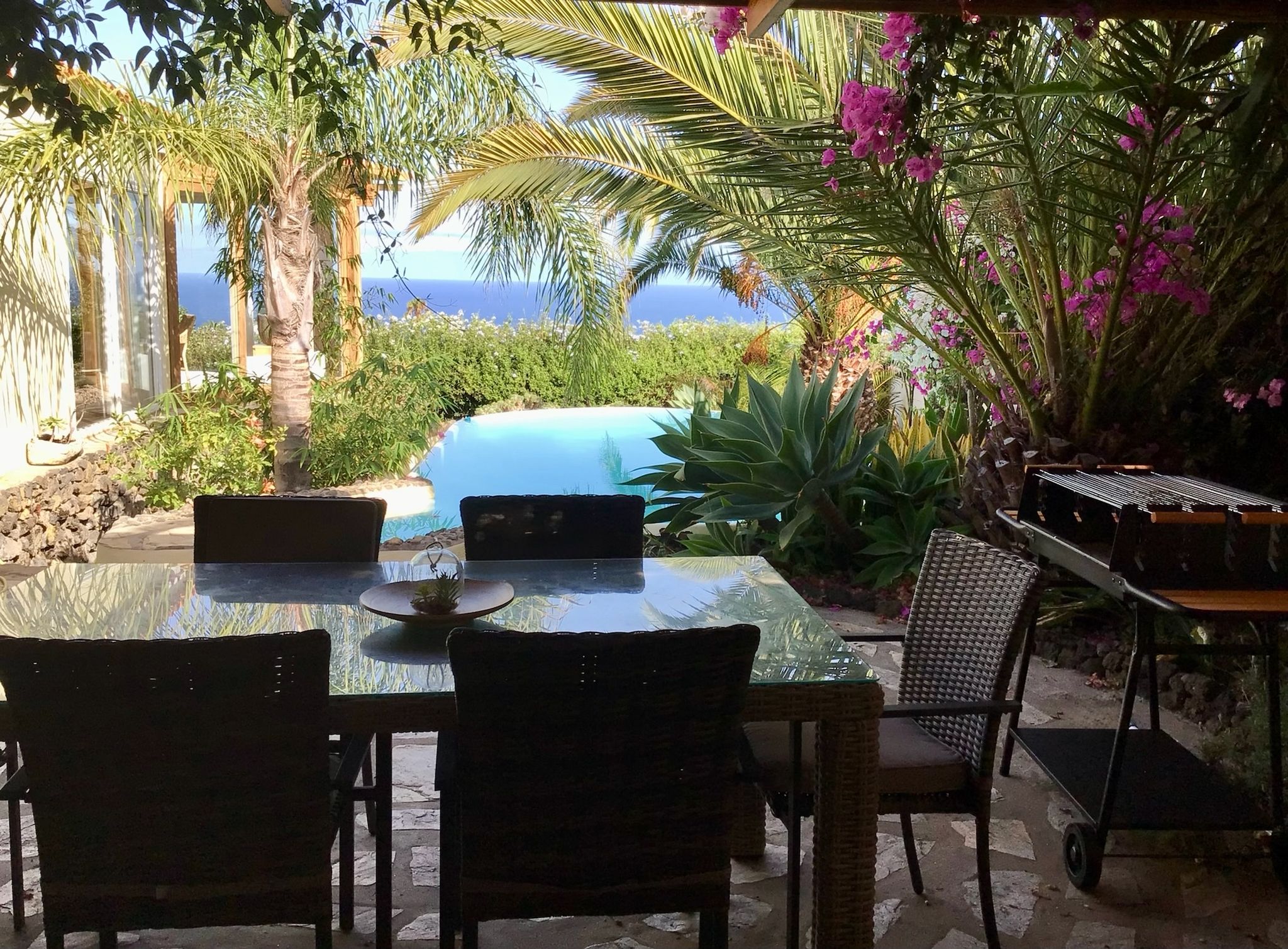 Bellamare: Überdachte Terrasse mit Esstisch und Grill, Blick auf Pool, Palmen und den Atlantik