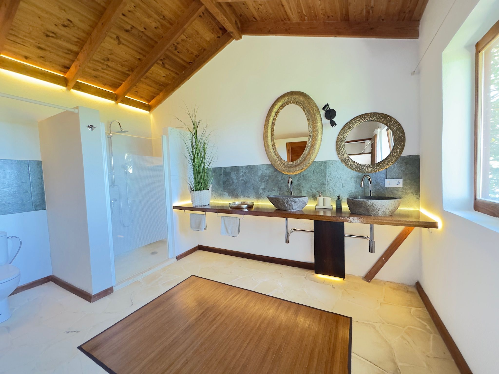 Bellamare: Badezimmer mit zwei Steinwaschbecken auf Holzablage, ebenerdiger Dusche und Holzdecke