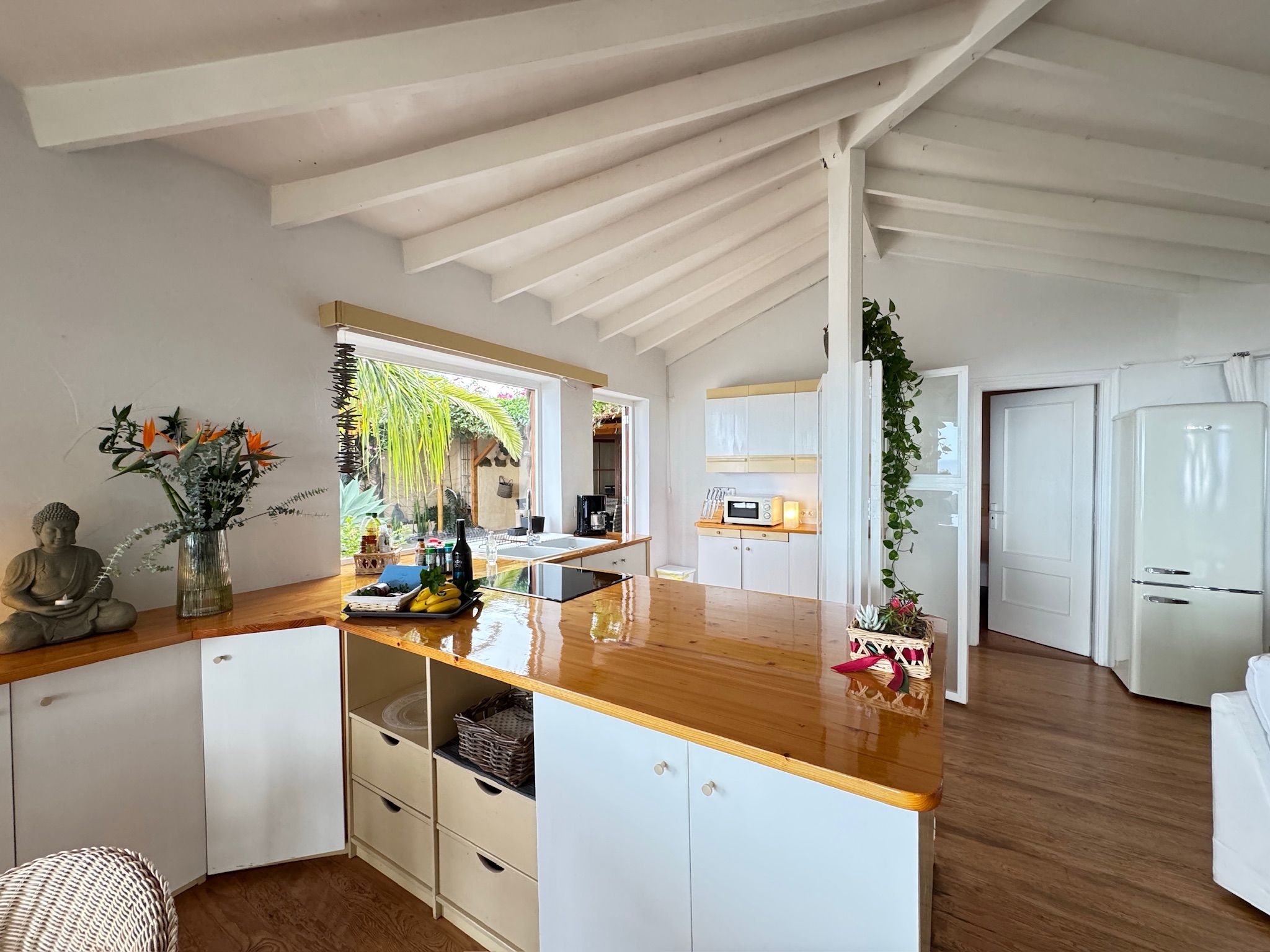 Bellamare: Offene Küche mit Holzarbeitsfläche, Ceranfeld und Kühlschrank im Retro-Stil unter weißen Deckenbalken