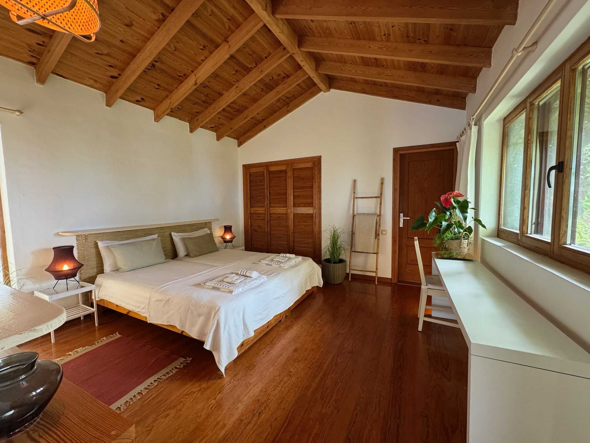 Bellamare: Schlafzimmer mit zwei Einzelbetten, Holzdecke, Einbauschrank und Fenster zum Garten
