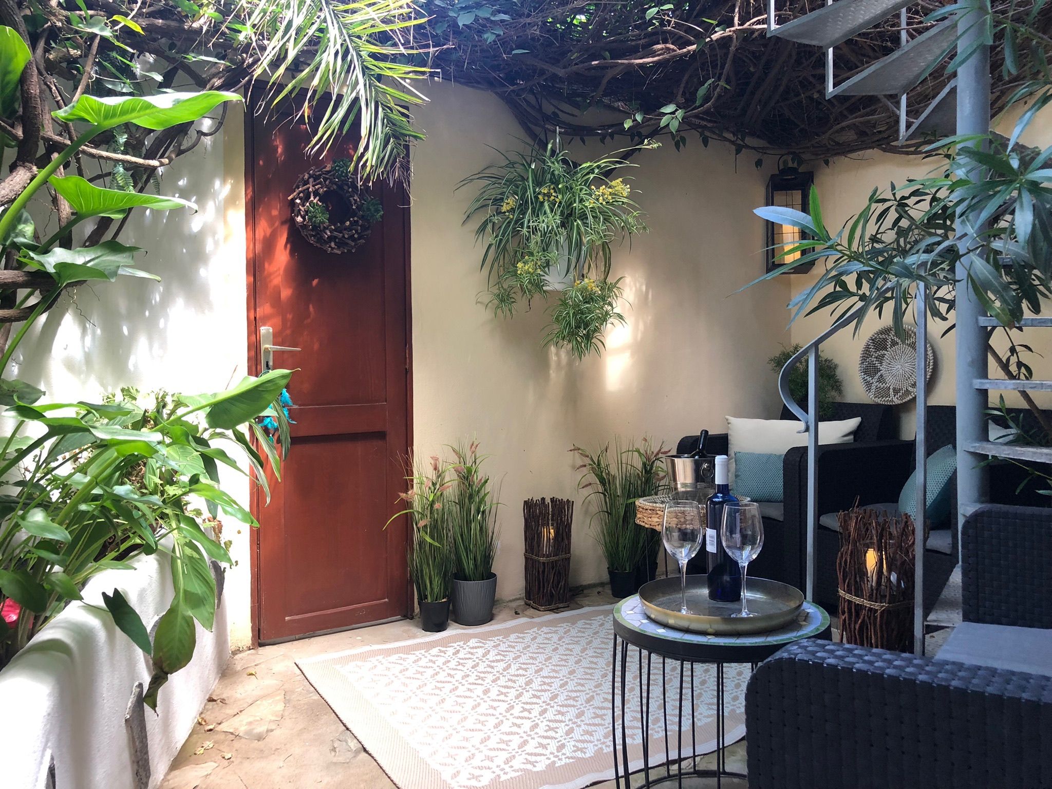 Casita Aquavista: Patio mit Holzeingangstür, Lounge-Sitzecke, Pflanzen und Wendeltreppe zur Dachterrasse
