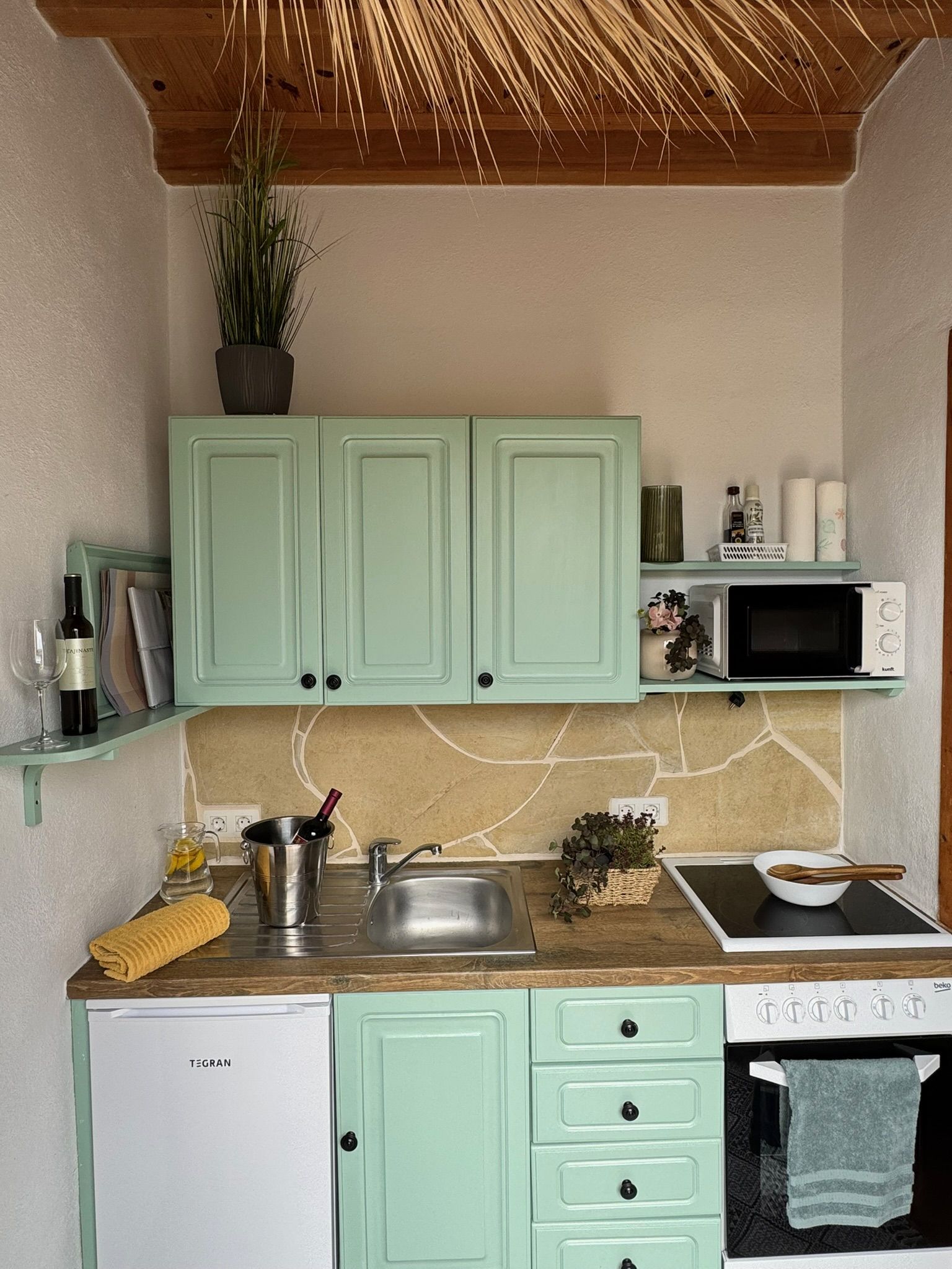 Casita Aquavista: Kleine Küche mit mintgrünen Schränken, Ceranfeld, Backofen, Mikrowelle und Kühlschrank