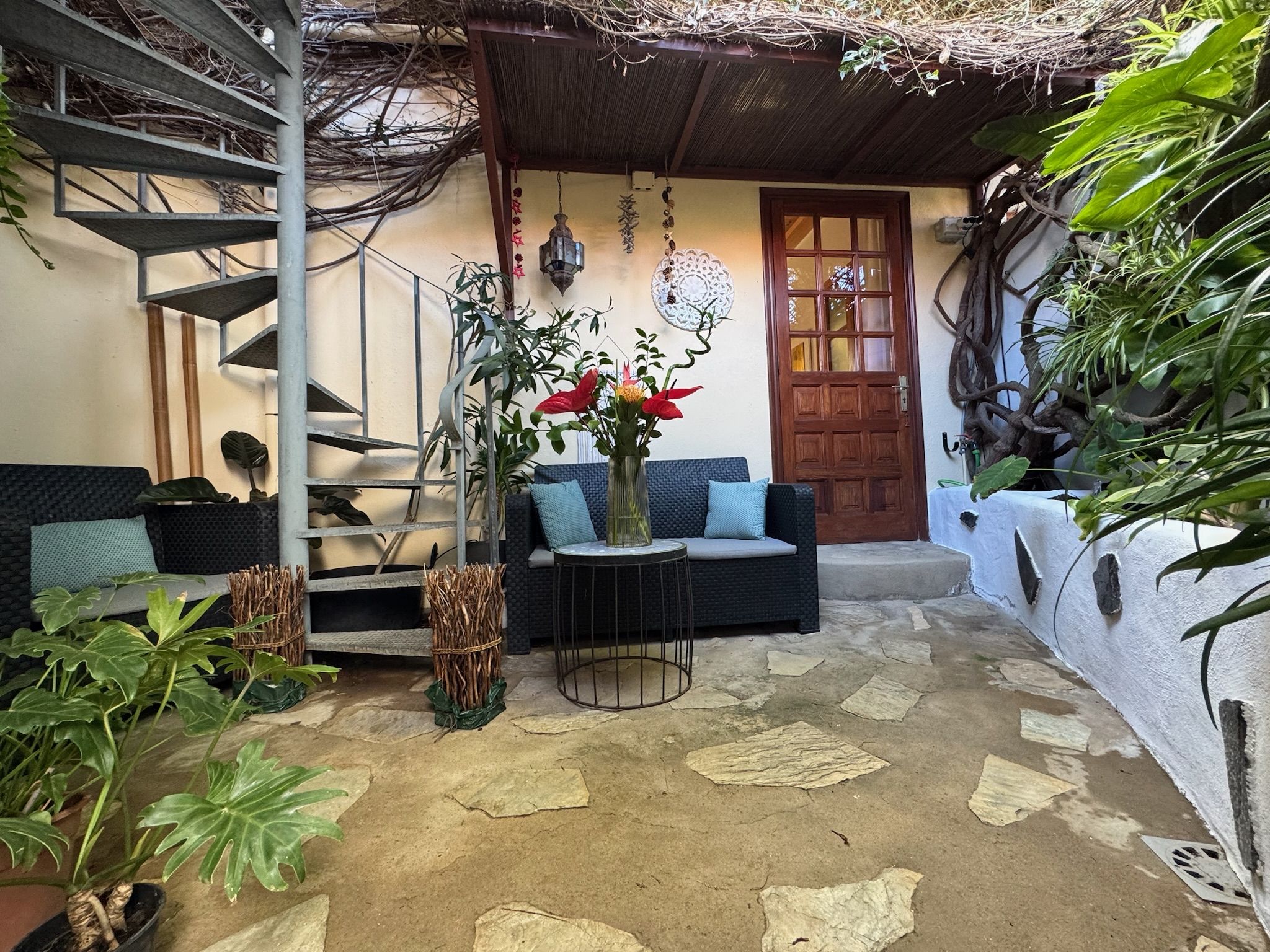 Casita Aquavista: Patio mit Natursteinboden, Sitzecke, Holzeingangstür und Wendeltreppe zur Dachterrasse